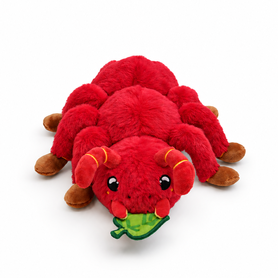 A red plush toy Ant with brown legs and feet, holding a green leaf in its paws, photographed on a clean white background.
